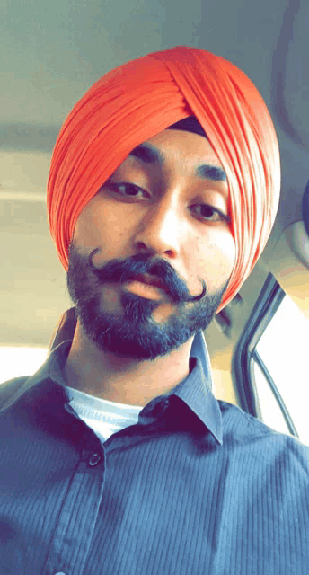 a man with a beard wearing an orange turban and a black shirt