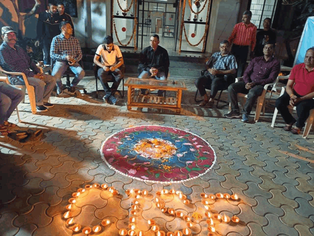 a group of men are sitting around a table with candles in the shape of the letter g