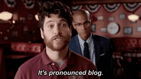 a man with a beard says it 's pronounced blog in front of a man in a suit
