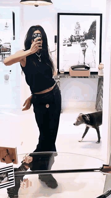 a woman is taking a picture of herself in a mirror with a dog in the background