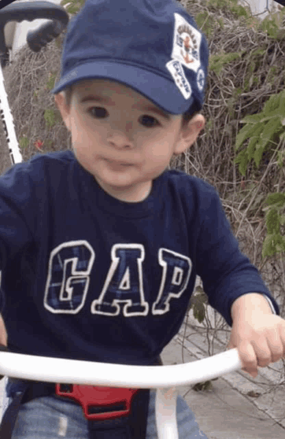 a little boy wearing a gap shirt and a blue hat