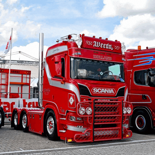 a red scania truck is parked next to another red truck