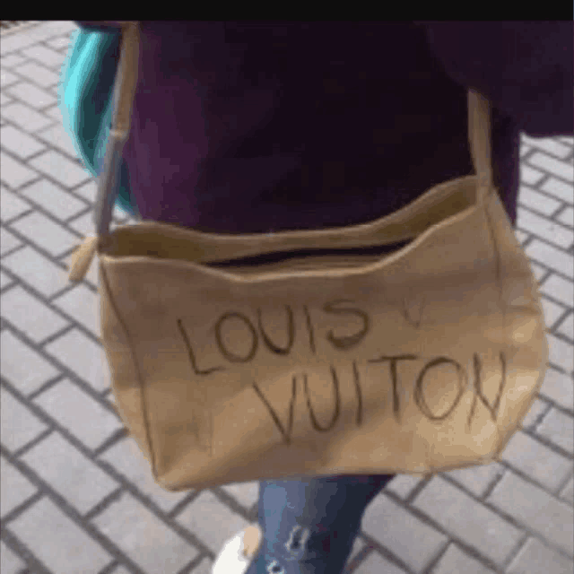 a person is carrying a brown louis vuitton purse