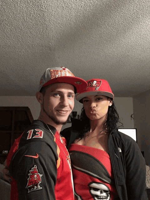 a man and a woman are posing for a picture and the man is wearing a tampa bay hat