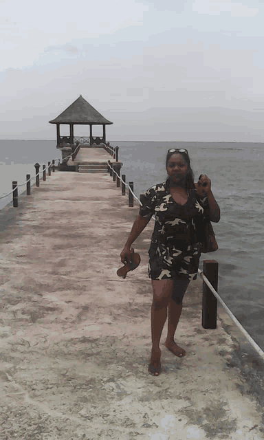 a woman standing on a dock with a gazebo in the distance