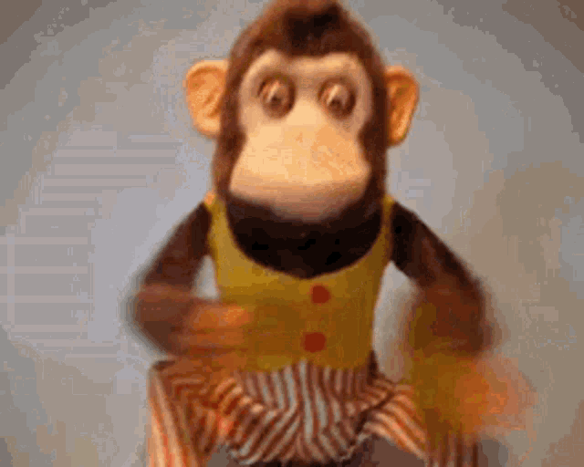 a stuffed monkey wearing striped shorts and a yellow shirt is dancing .