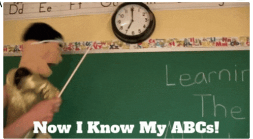 a teacher is pointing at a blackboard with the words " now i know my abcs "