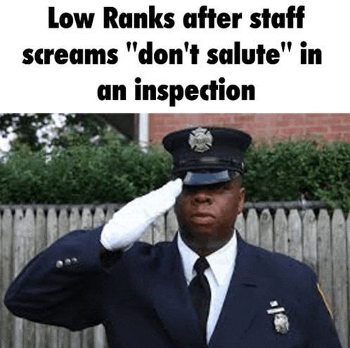 a police officer salutes in front of a wooden fence and says low ranks after staff