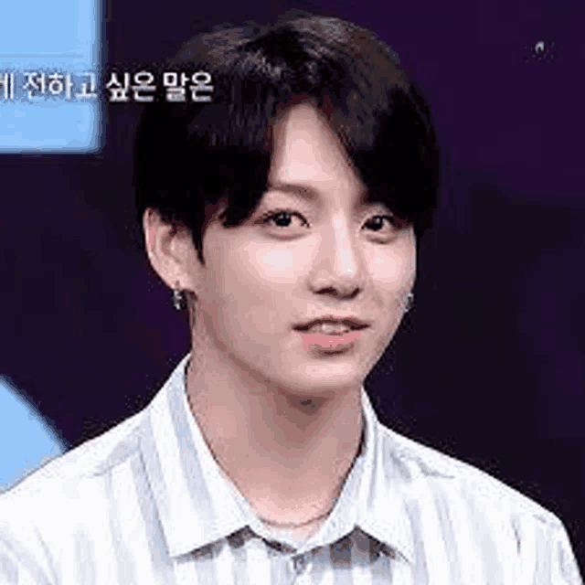 jungkook is wearing a striped shirt and earrings and looking at the camera .