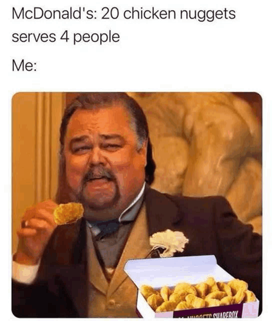 a man in a suit is holding a box of chicken nuggets and eating one .