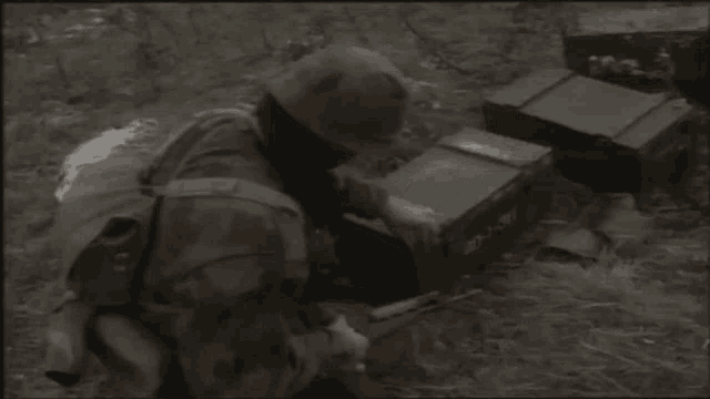 a man in a camouflage uniform is kneeling down next to a box that says ' a ' on the side