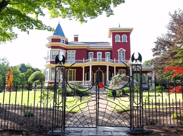 a large red house with a wrought iron gate leading to it