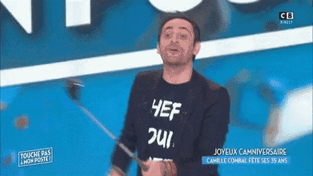 a man wearing a t-shirt that says hef oui is holding a stick .