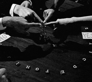 a black and white photo of people playing a game with letters on the table and a sign that says yes