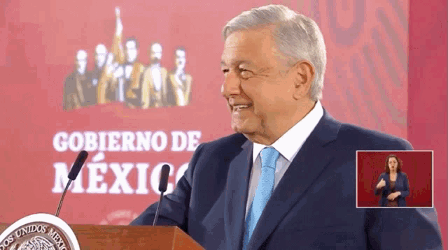 a man in a suit and tie stands at a podium in front of a sign that says " gobierno de mexico "