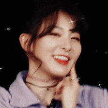 a close up of a woman wearing a choker and a purple shirt smiling .