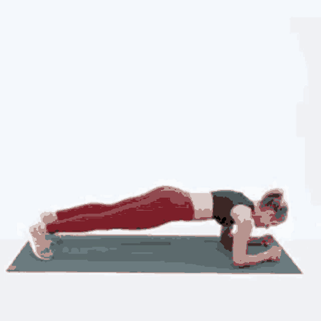 a woman is doing a plank on a yoga mat with her legs crossed .