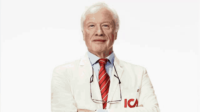 a man in a white coat and red tie has ica written on his sleeve