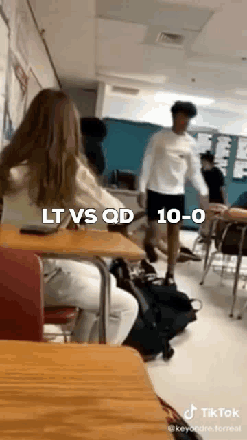 a group of students are sitting at desks in a classroom with a man standing in front of them .