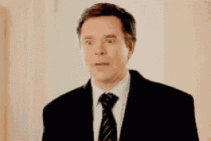 a man in a suit and tie making a surprised face