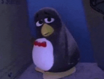 a stuffed penguin wearing a red bow tie is sitting on a table .