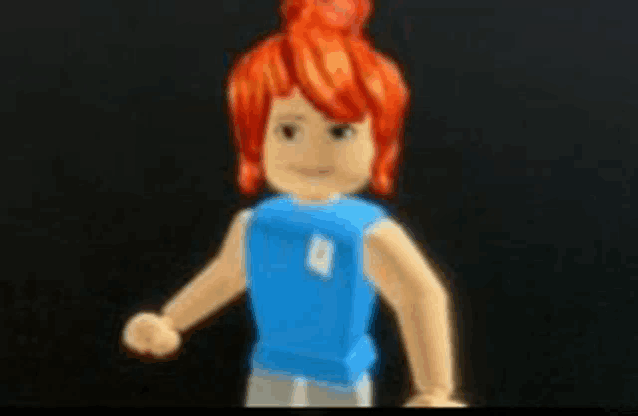 a toy boy with red hair and a blue shirt is standing on a black surface .