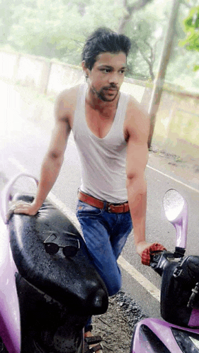 a man in a white tank top leans against a purple motorcycle