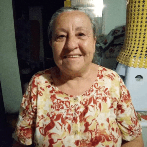 an older woman wearing a floral shirt is smiling for the camera