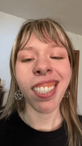 a woman with a nose ring and a pentagram earrings smiles