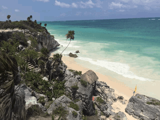 a beach with a thatched hut on the cliff