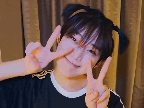 a person with pigtails on their head is giving a peace sign