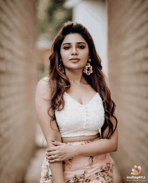 a woman wearing a white crop top and floral skirt poses for a photo with indiaglitz