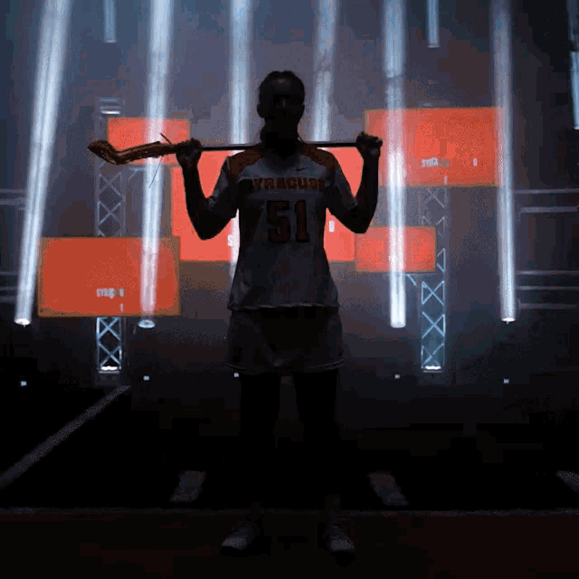 a woman holding a lacrosse stick with the number 51 on her jersey