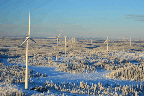 a row of wind turbines in the middle of a snowy field