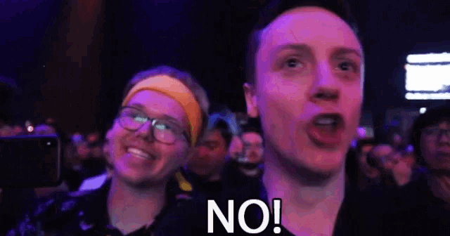 a man is screaming in a crowd with the word no written on his face .