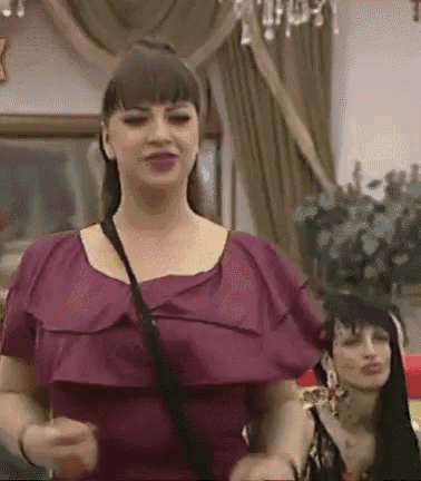 a woman in a purple dress is standing next to another woman in a living room .