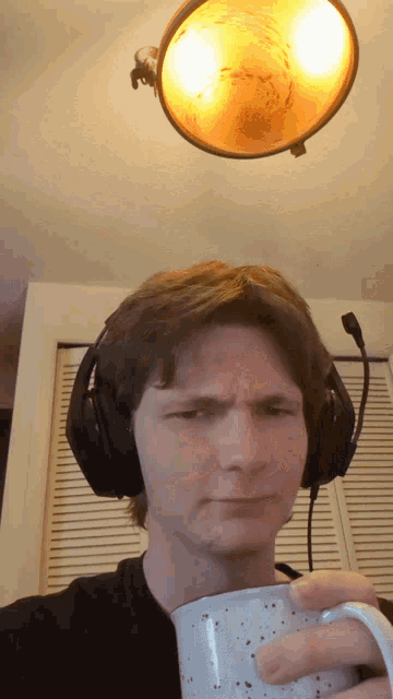 a man wearing headphones is holding a coffee cup