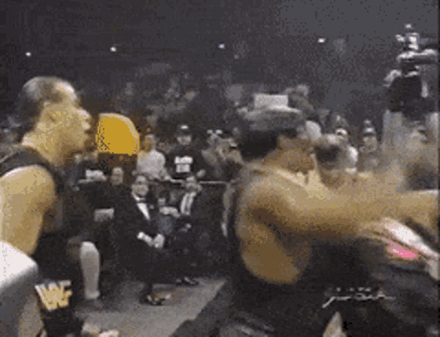 a group of wrestlers are fighting in front of a crowd and one of them has a wcf logo on his chest