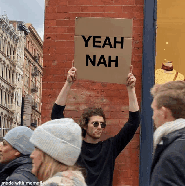 a man holding a sign that says yeah nah