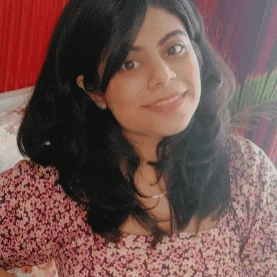 a woman with long dark hair is wearing a pink floral shirt and smiling .