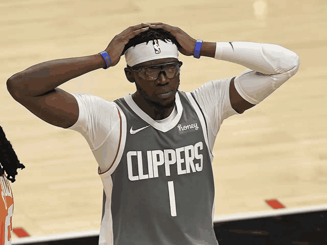 a basketball player wearing glasses and a clippers jersey holds his head