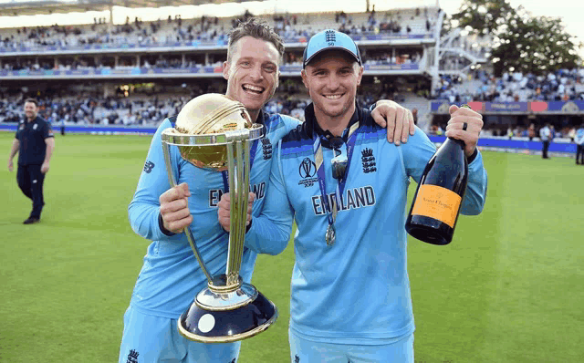 two england players holding a trophy and a bottle