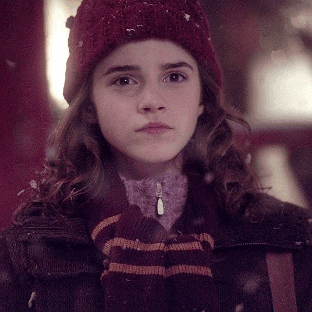 a young girl wearing a red hat and a striped scarf