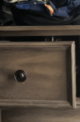 a gray drawer with a black knob and a black bag in it