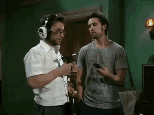 two men are standing next to each other in a room with headphones on .