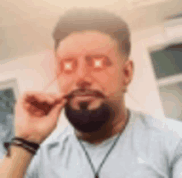 a man with a beard is taking a selfie with his eyes glowing .