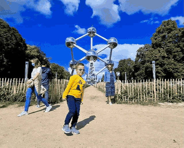 a boy wearing a yellow shirt that says ' i love you ' on it stands in front of a ferris wheel