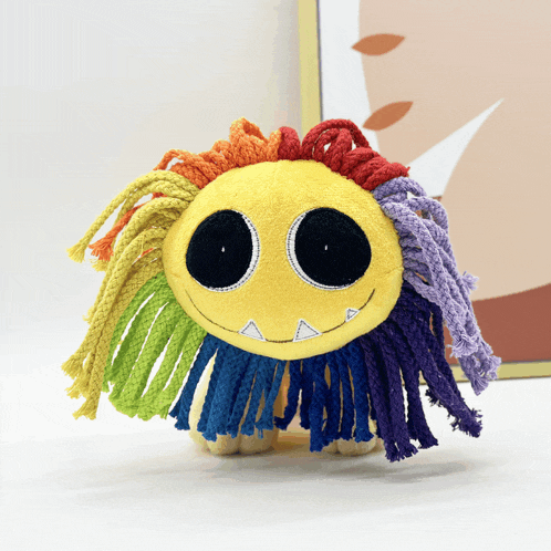 a stuffed animal with a rainbow haired face and teeth