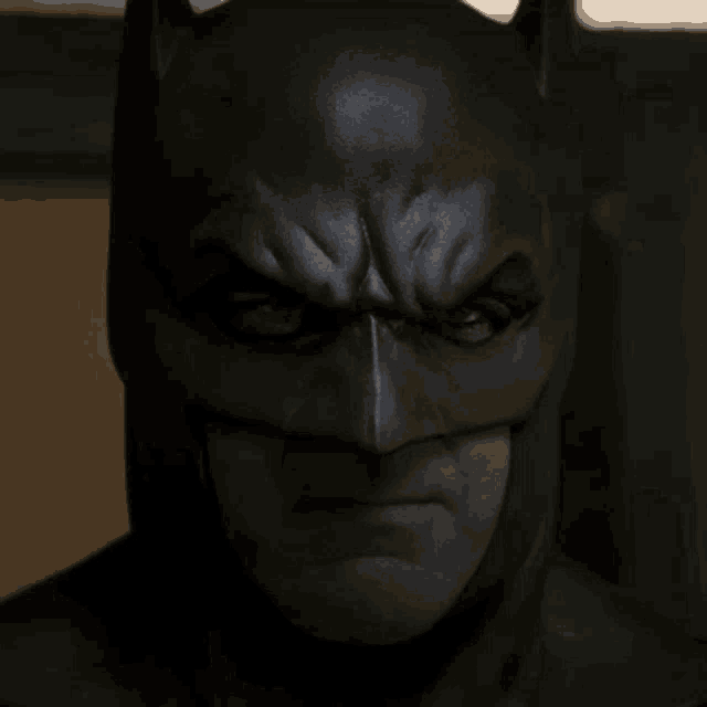 a close up of a man wearing a batman mask making an angry face