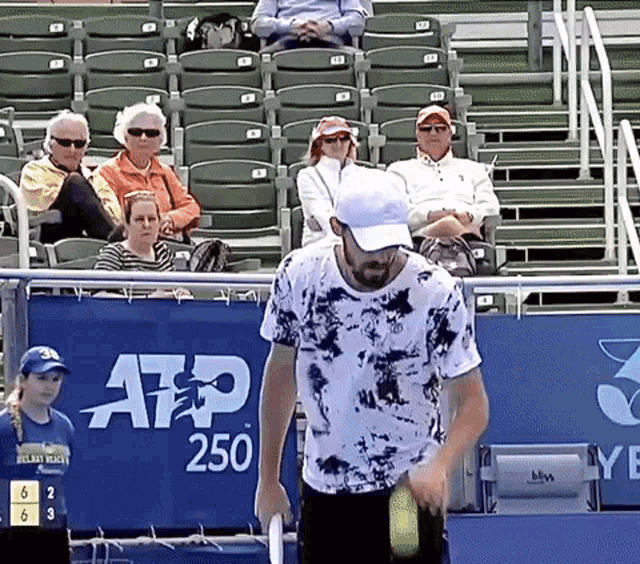 a man in a tie dye shirt is holding a tennis racquet in front of a banner that says atp 250